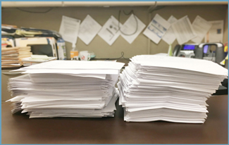 Figure 8 is a photo of two tall stacks of paper that represent a single hardcopy report.